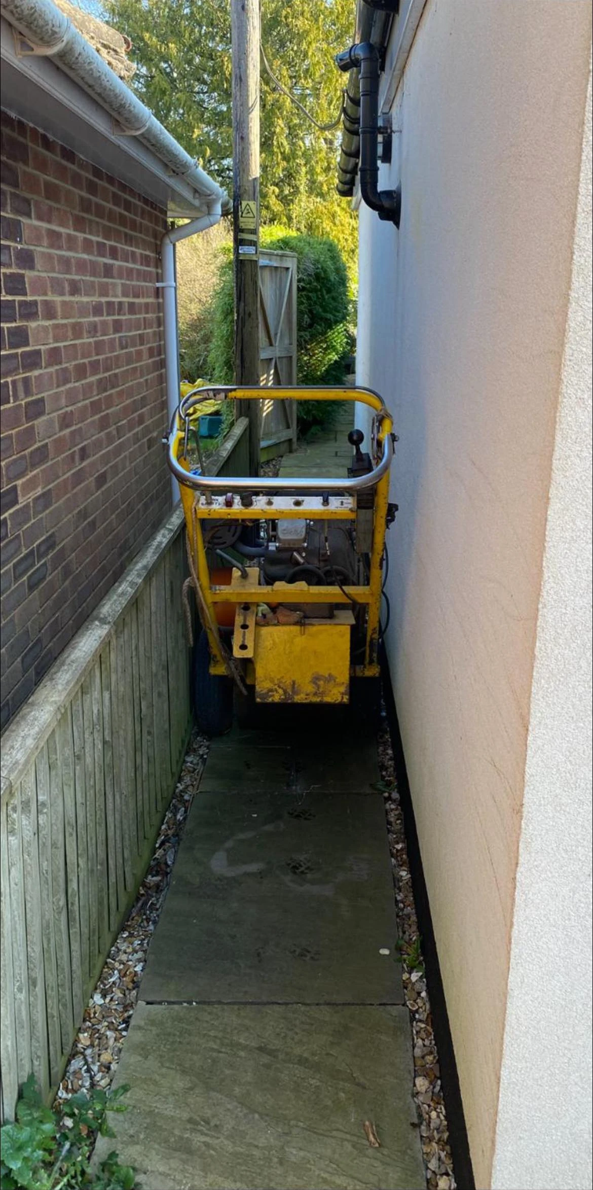 Grinding machine down the alley way of a house.